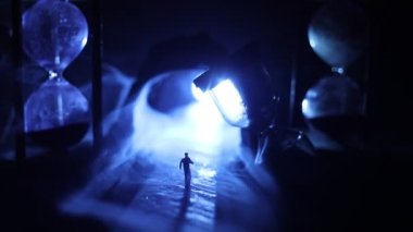 Zaman kavramı. Kum bir kum saati için bir son tarih saymak aşağı olarak geçen süre ölçümünü cam ampuller geçiyor. Hourglasses Silhouette koyu arka plan üzerinde duman. Çiçeklerle