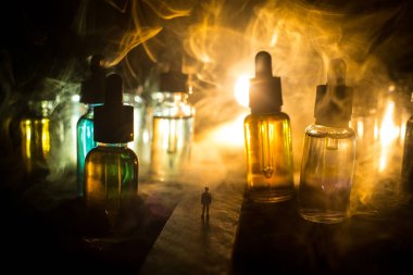 Vape kavramı. Sisli bir gecede dev cam şişe ile yolun ortasında duran bir adam silüeti elektronik sigara sıvı ile dolu. Işık arka plan üzerinde renkli sisli bulutlar.