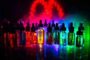 Vape kavramı. Duman bulutları ve vape sıvı şişe koyu arka plan üzerinde. Işık efektleri. Arka plan veya elektronik sigara reklam olarak kullanışlıdır. Seçici odak