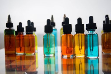 Vape kavramı. Güzel renkli vape sıvı cam şişeler satranç tahtası üzerinde açık. Arka plan veya elektronik sigara reklam olarak kullanışlıdır. Seçici odak