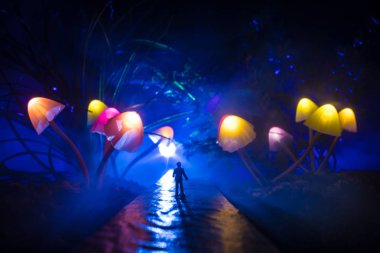 Fantezi dev parlayan mantar orman yürüyüş. Bir adam yolun ortasında sisli bir gecede dev fantezi parlayan ayakta silüeti yol her iki tarafında mantar.