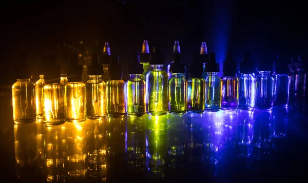 Vape kavramı. Duman bulutları ve vape sıvı şişe koyu arka plan üzerinde. Işık efektleri. Arka plan veya elektronik sigara reklam olarak kullanışlıdır. Seçici odak