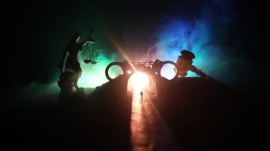 Hukuk hukuku ya da suç kavramı. Sisli bir gecede yolun ortasında tek başına duran bir adam. Kelepçeli sanat dekorasyonu, Adalet Heykeli ve sisli arka planda adalet tokmağı..