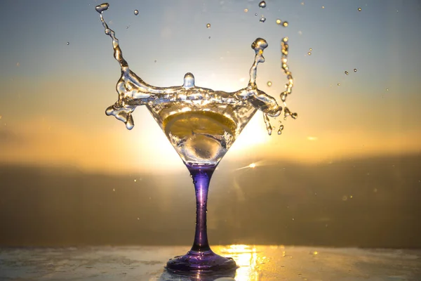Martini cocktailglas i hand stänk på mörk tonad rökig bakgrund eller färggrann cocktail i glas med färgstänk och Oliver. Party club underhållning. Blandade ljus. Selektivt fokus — Stockfoto