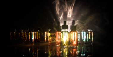 Vape kavramı. Duman bulutları ve vape sıvı şişe koyu arka plan üzerinde. Işık efektleri. Arka plan veya elektronik sigara reklam olarak kullanışlıdır. Seçici odak