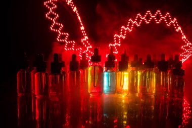Vape kavramı. Duman bulutları ve vape sıvı şişe koyu arka plan üzerinde. Işık efektleri. Arka plan veya elektronik sigara reklam olarak kullanışlıdır. Seçici odak