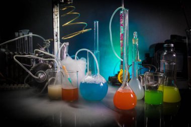 Eczane ve kimya teması. Araştırma laboratuarında çözeltisi olan cam deney şişesi. Bilim ve tıbbi geçmiş. Koyu renk arkaplan üzerinde laboratuvar test tüpleri, bilimsel araştırma ekipmanları konsepti