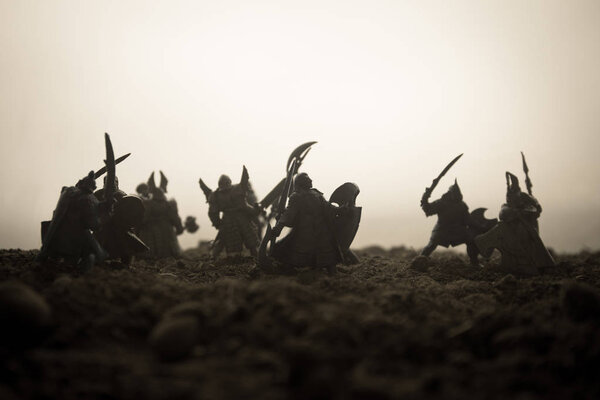 Medieval battle scene with cavalry and infantry. Silhouettes of figures as separate objects, fight between warriors on sunset foggy background. Artwork decoration. Selective focus