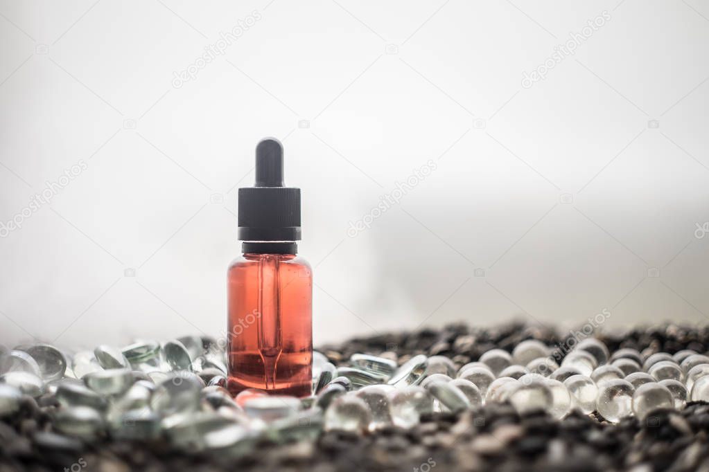 Vape concept. Beautiful colorful vape liquid glass bottles outdoor on stones. Useful as background or electronic cigarette advertisement. Selective focus