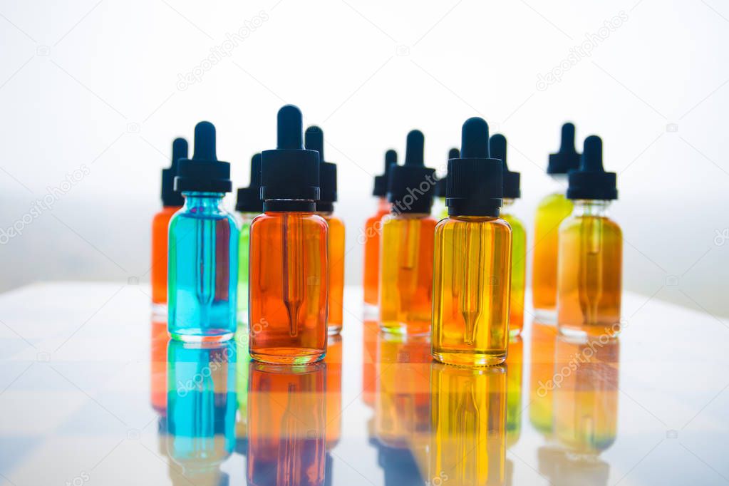 Vape concept. Beautiful colorful vape liquid glass bottles outdoor on chessboard. Useful as background or electronic cigarette advertisement. Selective focus