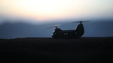 Askeri helikopter çatışma bölgesinden uçmaya hazır silüeti. Gece görüntüleri çöl sisli tonda sırt ile başlayarak helikopter ile dekore edilmiştir. Seçici odak.