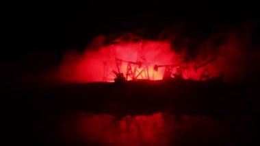 Sanat dekorasyonu. Petrol savaş konsepti. Petrol sahasında pompa ve kuleleri olan askeri siluetler. Misty renkli gökyüzü arka plan. Zırhlı araçlar dövüş sahnesi. 