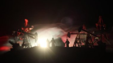 Sanat dekorasyonu. Petrol savaş konsepti. Petrol sahasında pompa ve kuleleri olan askeri siluetler. Misty renkli gökyüzü arka plan. Zırhlı araçlar dövüş sahnesi. 