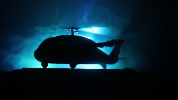 Силуэт военного вертолета, готового вылететь из зоны конфликта. Украшенные ночные кадры с вертолетом, начинающимся в пустыне с туманной подсветкой. Селективный фокус . — стоковое видео