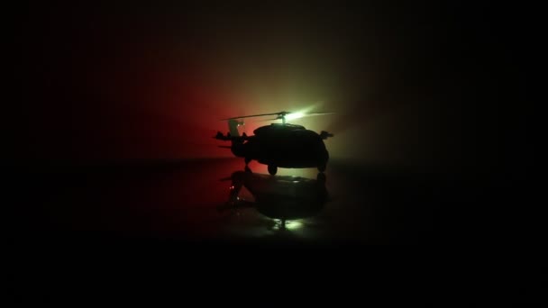 Silhueta de helicóptero militar pronta para voar da zona de conflito. Filmagem noturna decorada com helicóptero começando no deserto com nevoeiro tonificado retroiluminado. Foco seletivo . — Vídeo de Stock