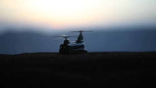 Silhueta de helicóptero militar pronta para voar da zona de conflito. Filmagem noturna decorada com helicóptero começando no deserto com nevoeiro tonificado retroiluminado. Foco seletivo . — Vídeo de Stock