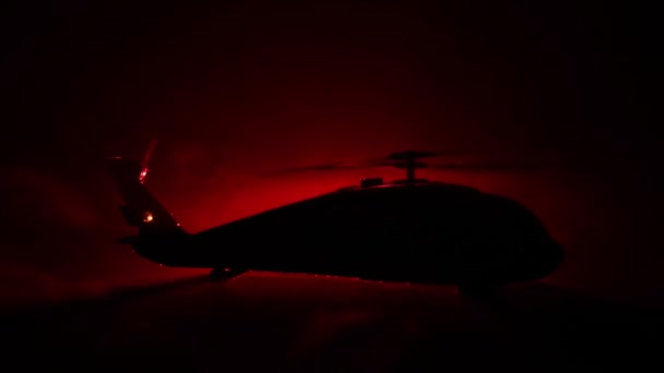 Silhouet van militaire helikopter klaar om te vliegen vanaf conflictgebied. Nacht beelden versierd met helikopter starten in woestijn met mistige afgezwakt achtergrondverlichting. Selectieve aandacht. — Stockvideo