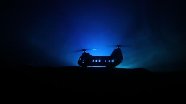 Silhueta de helicóptero militar pronta para voar da zona de conflito. Filmagem noturna decorada com helicóptero começando no deserto com nevoeiro tonificado retroiluminado. Foco seletivo . — Vídeo de Stock