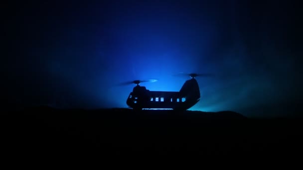 Silueta de helicóptero militar lista para volar desde zona de conflicto. Imágenes nocturnas decoradas con helicóptero comenzando en el desierto con niebla tonificada retroiluminada. Enfoque selectivo . — Vídeos de Stock