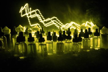Vape kavramı. Duman bulutları ve vape sıvı şişe koyu arka plan üzerinde. Işık efektleri. Arka plan veya elektronik sigara reklam olarak kullanışlıdır. Seçici odak