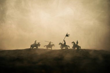 Süvari ve piyade ile ortaçağ savaş sahnesi. Siluetleri şekiller ayrı nesneler olarak mücadele günbatımı sisli arka plan savaşçılar arasında. Seçici odak