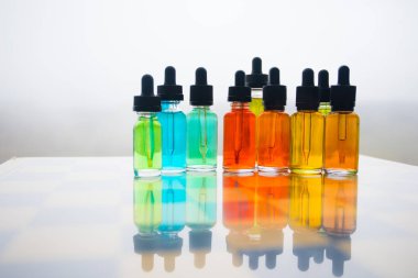 Vape kavramı. Güzel renkli vape sıvı cam şişeler satranç tahtası üzerinde açık. Arka plan veya elektronik sigara reklam olarak kullanışlıdır. Seçici odak