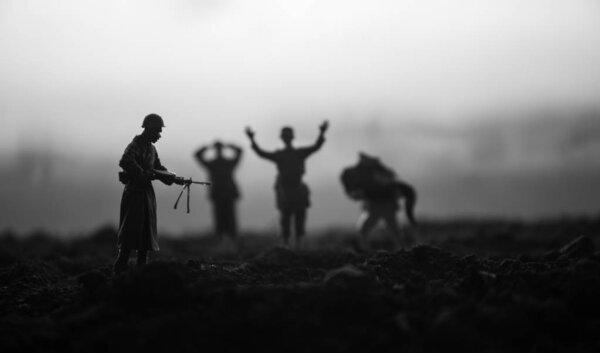 Battle scene. Military silhouettes fighting scene on war fog sky background. A German soldiers raised arms to surrender. Plastic toy soldiers with guns taking prisoner the enemy soldier. Artwork