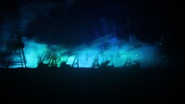 Sanat dekorasyonu. Petrol savaş konsepti. Petrol sahasında pompa ve kuleleri olan askeri siluetler. Misty renkli gökyüzü arka plan. Zırhlı araçlar dövüş sahnesi. 