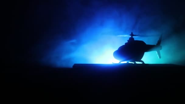 Silhueta de helicóptero militar pronta para voar da zona de conflito. Filmagem noturna decorada com helicóptero começando no deserto com nevoeiro tonificado retroiluminado. Foco seletivo . — Vídeo de Stock