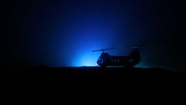 Silhueta de helicóptero militar pronta para voar da zona de conflito. Filmagem noturna decorada com helicóptero começando no deserto com nevoeiro tonificado retroiluminado. Foco seletivo . — Vídeo de Stock