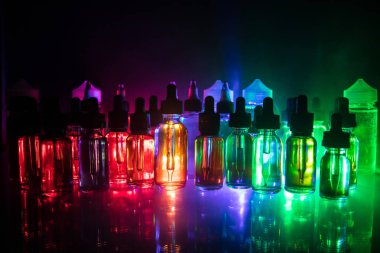 Vape kavramı. Duman bulutları ve vape sıvı şişe koyu arka plan üzerinde. Işık efektleri. Arka plan veya elektronik sigara reklam olarak kullanışlıdır. Seçici odak