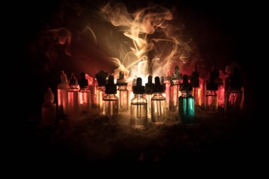 Vape kavramı. Duman bulutları ve vape sıvı şişe koyu arka plan üzerinde. Işık efektleri. Arka plan veya elektronik sigara reklam olarak kullanışlıdır. Seçici odak