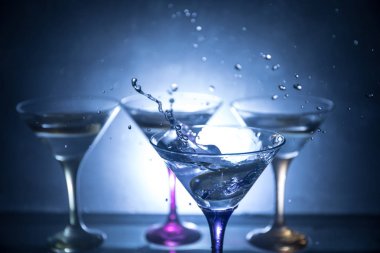 Martini kokteyl cam karanlık sıçramasına dumanlı arka plan veya renkli kokteyl cam su sıçramalarına ve limon ile tonda. Parti club eğlence. Karışık ışık. Seçici odak