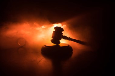 Hukuk tema, hakimin adalet heykeli ile ahşap masa üzerinde çekiç. Işık ile karanlık sisli zemin üzerine hukuk tokmak. Seçici odak