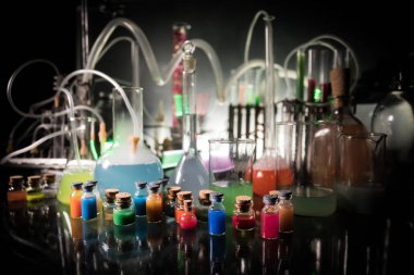 Eczane ve kimya teması. Araştırma laboratuarında çözeltisi olan cam deney şişesi. Bilim ve tıbbi geçmiş. Koyu renk arkaplan üzerinde laboratuvar test tüpleri, bilimsel araştırma ekipmanları konsepti