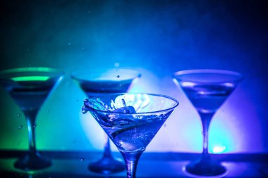 Martini kokteyl cam karanlık sıçramasına dumanlı arka plan veya renkli kokteyl cam su sıçramalarına ve limon ile tonda. Parti club eğlence. Karışık ışık. Seçici odak
