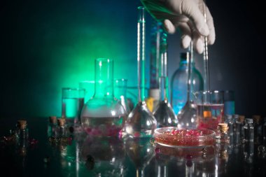Eczane ve kimya teması. Araştırma laboratuarında çözeltisi olan cam deney şişesi. Bilim ve tıbbi geçmiş. Koyu renk arkaplan üzerinde laboratuvar test tüpleri, bilimsel araştırma ekipmanları konsepti