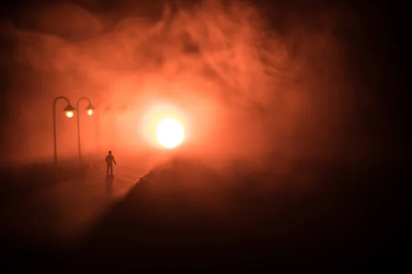 艺术品装饰 一个人晚上走在路上 在一个雾蒙蒙的夜晚 一个男人站在路中间的轮廓 路灯对着雾的耀眼光芒 让人产生了一种令人毛骨悚然的心情 — 图库照片