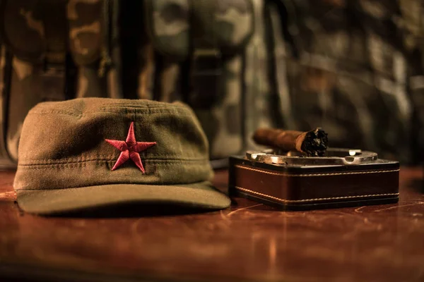 Close up of a Cuban cigar and ashtray on the wooden table. Communist dictator commander table in dark room. Army general`s work table concept. Artwork decoration