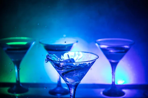 暗闇ではねかけるマティーニ カクテル グラス トーン スモーキーな背景やガラスの飛散とレモンのカラフルなカクテル パーティー プールクラブ エンタテインメント 混合光 選択と集中 — ストック写真