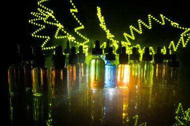 Vape kavramı. Duman bulutları ve vape sıvı şişe koyu arka plan üzerinde. Işık efektleri. Arka plan veya elektronik sigara reklam olarak kullanışlıdır. Seçici odak