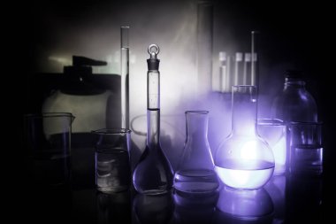Eczane ve kimya teması. Araştırma laboratuarında çözeltisi olan cam deney şişesi. Bilim ve tıbbi geçmiş. Koyu renk arkaplan üzerinde laboratuvar test tüpleri, bilimsel araştırma ekipmanları konsepti