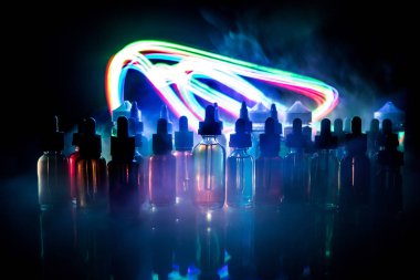 Vape kavramı. Duman bulutları ve vape sıvı şişe koyu arka plan üzerinde. Işık efektleri. Arka plan veya elektronik sigara reklam olarak kullanışlıdır. Seçici odak