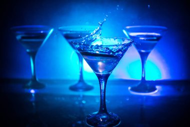 Martini kokteyl cam karanlık sıçramasına dumanlı arka plan veya renkli kokteyl cam su sıçramalarına ve limon ile tonda. Parti club eğlence. Karışık ışık. Seçici odak