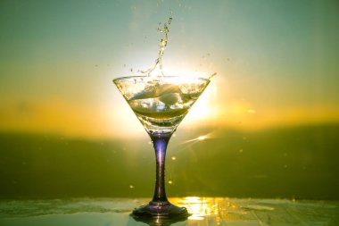 Martini kokteyl cam sisli gün batımı arka plan veya renkli kokteyl cam su sıçramalarına ve limon ile sıçramasına. Açık açık hava parti eğlence. Seçici odak