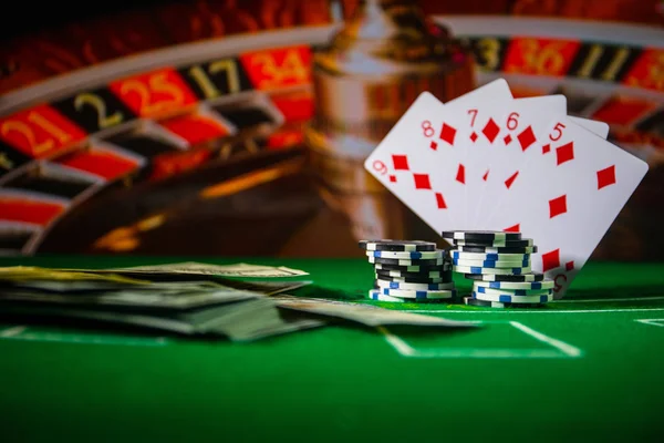 Cards and chips on green felt casino table. Abstract background with copy space. Gambling, poker, casino and cards games theme. Casino elements on green. Selective focus