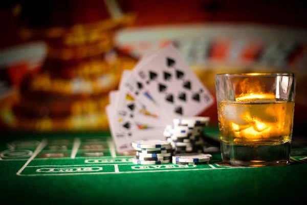 gambling, fortune, game and entertainment concept - close up of casino chips and whisky glass on table. Selective focus