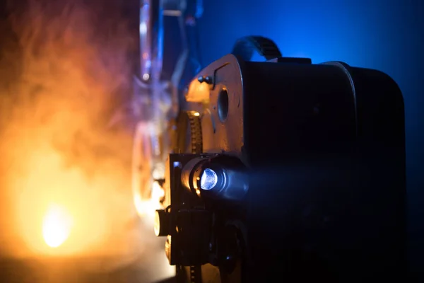 Old vintage movie projector on a dark background with fog and light. Concept of film-making. Selective focus