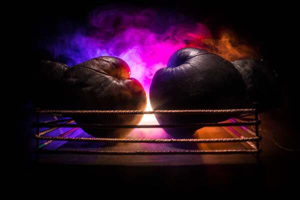 Empty boxing ring with red ropes for match in the stadium arena. Boxing gloves ready to fight. Empty space for text. Foggy background with light. Selective focus