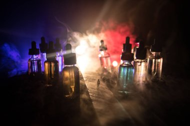 Vape kavramı. Sisli bir gecede dev cam şişe ile yolun ortasında duran bir adam silüeti elektronik sigara sıvı ile dolu. Işık arka plan üzerinde renkli sisli bulutlar.